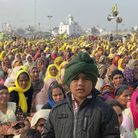 Image of a crowd of people, many with yellow scarves on their heads.