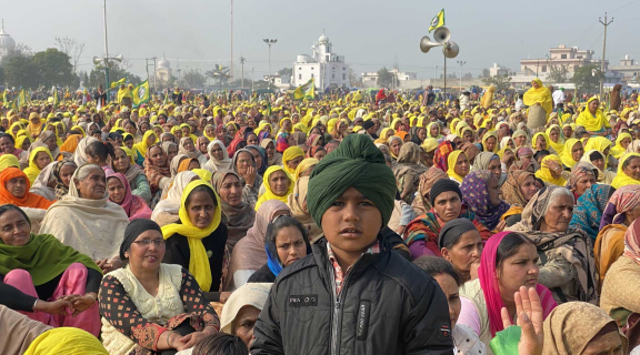 Image of a crowd of people, many with yellow scarves on their heads.